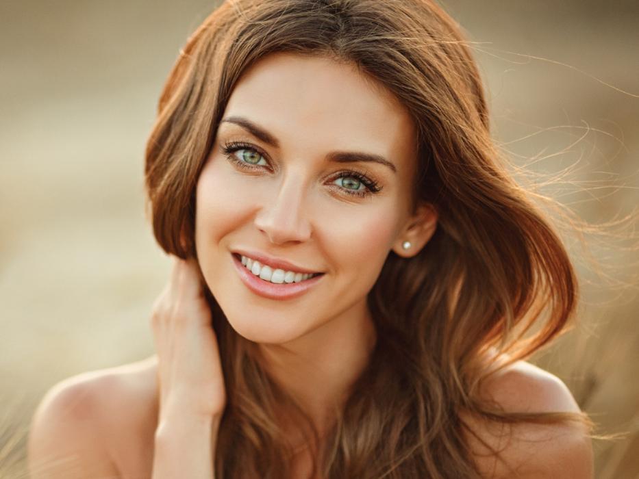 woman smiling holding her neck