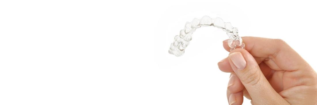 Hand holding Invisalign clear braces in Aurora, IL