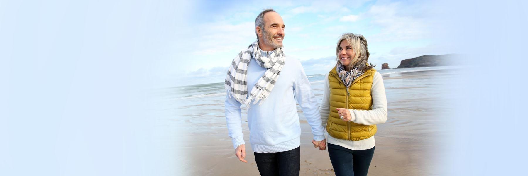 Older couple walking on beach | Dentist Aurora IL